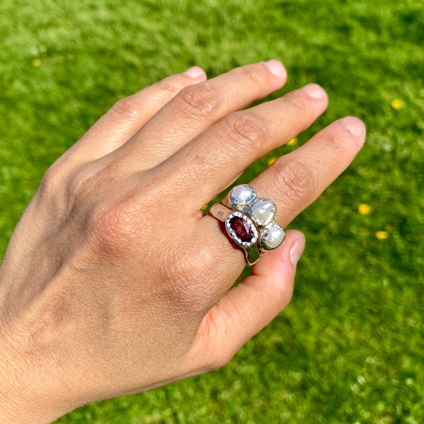 Double Harmony Rings come in a set of two. One ring features a pink tourmaline stone, and the other features three small pearl stones. Handmade from sterling silver, these stacking rings come in a single size: O ½ (or 7 ¼).