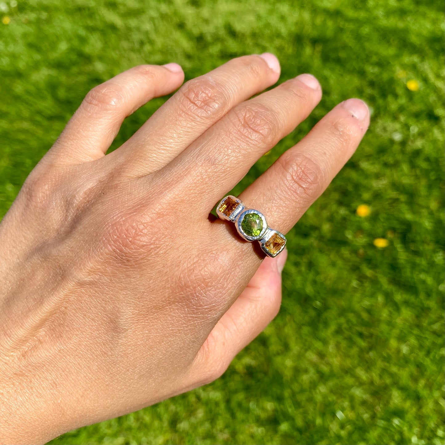 Citrus Garden Ring features a green peridot stone and two square, yellow citrines on the sides. Handmade from sterling silver, this ring comes in a single size: N ½ (or 6 ¾).