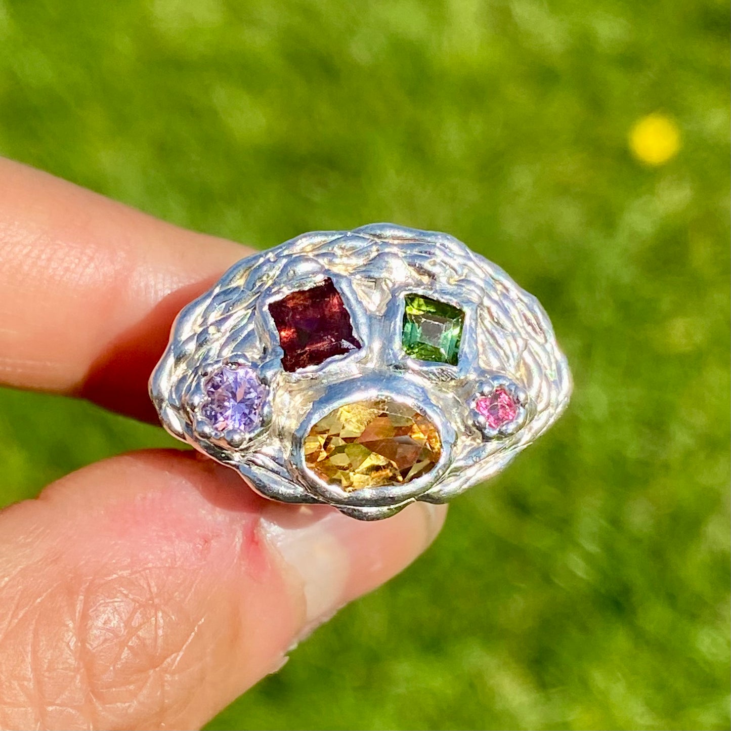 Inspired by a rainbow nestled in a crown, the Crown Rainbow Ring features a dazzling combination of gemstones. An oval yellow citrine gemstone, complemented by pink and green tourmalines, and two light pink and clear stones, all set in a chunky band. Handmade from sterling silver, it comes in a single size: M ½ or 6 ¼.