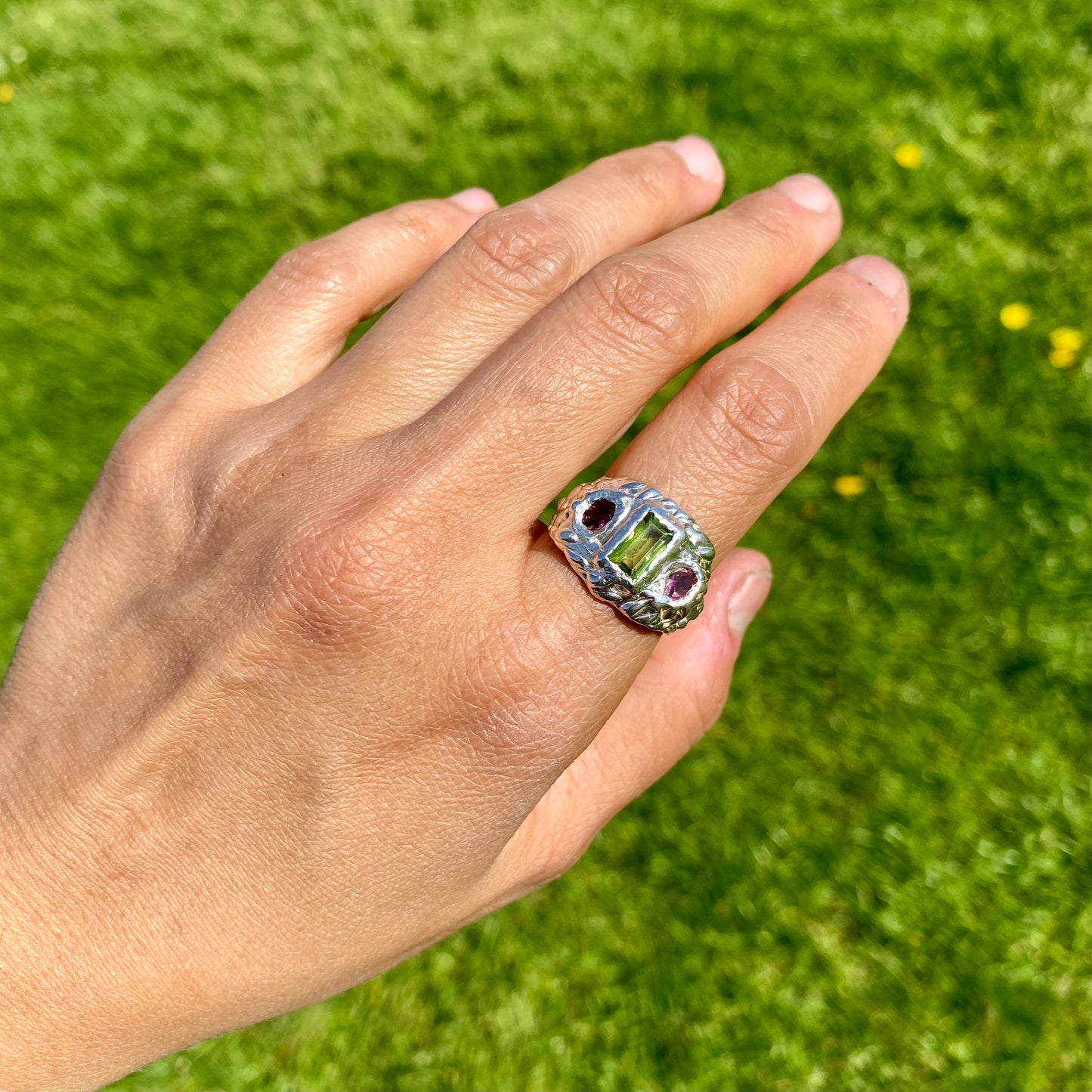 Cute Fish Face Ring features a green peridot stone and two pink tourmalines, set in a chunky band. Handmade from sterling silver, this ring comes in a single size: M ½ (or US size 6 ¼).