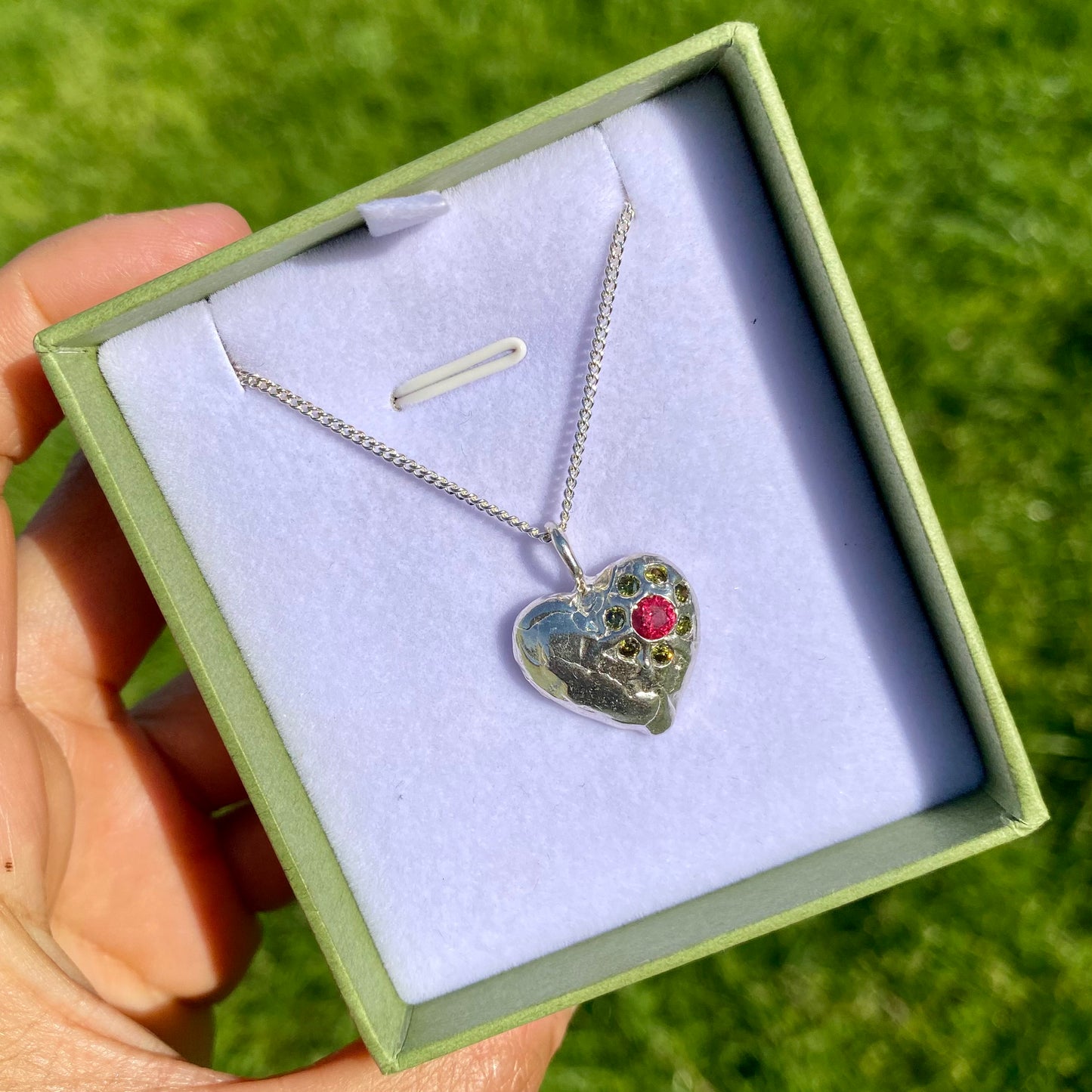 Full Bloom Heart Pendants are a collection of two handcrafted pendants, each blossoming with vibrant gemstones. Choose between a cheerful yellow and pink combination or a festive red and green pairing. Each pendant features eight sparkling stones, ready to capture your heart.