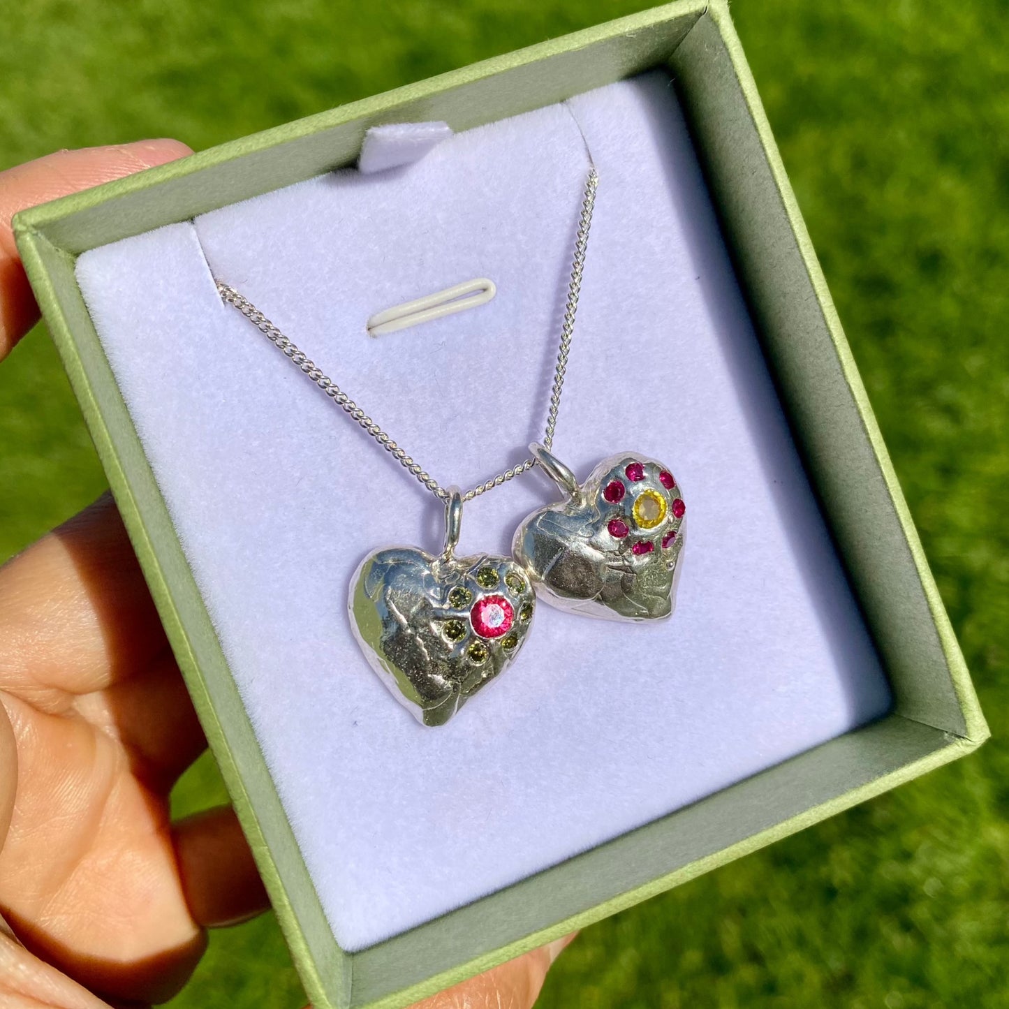 Full Bloom Heart Pendants are a collection of two handcrafted pendants, each blossoming with vibrant gemstones. Choose between a cheerful yellow and pink combination or a festive red and green pairing. Each pendant features eight sparkling stones, ready to capture your heart.