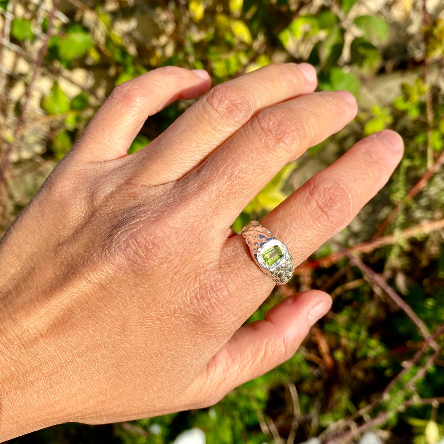 Leafy ring shown in my hand. With green peridot stone, this ring is handmade by Lia in sterling silver.