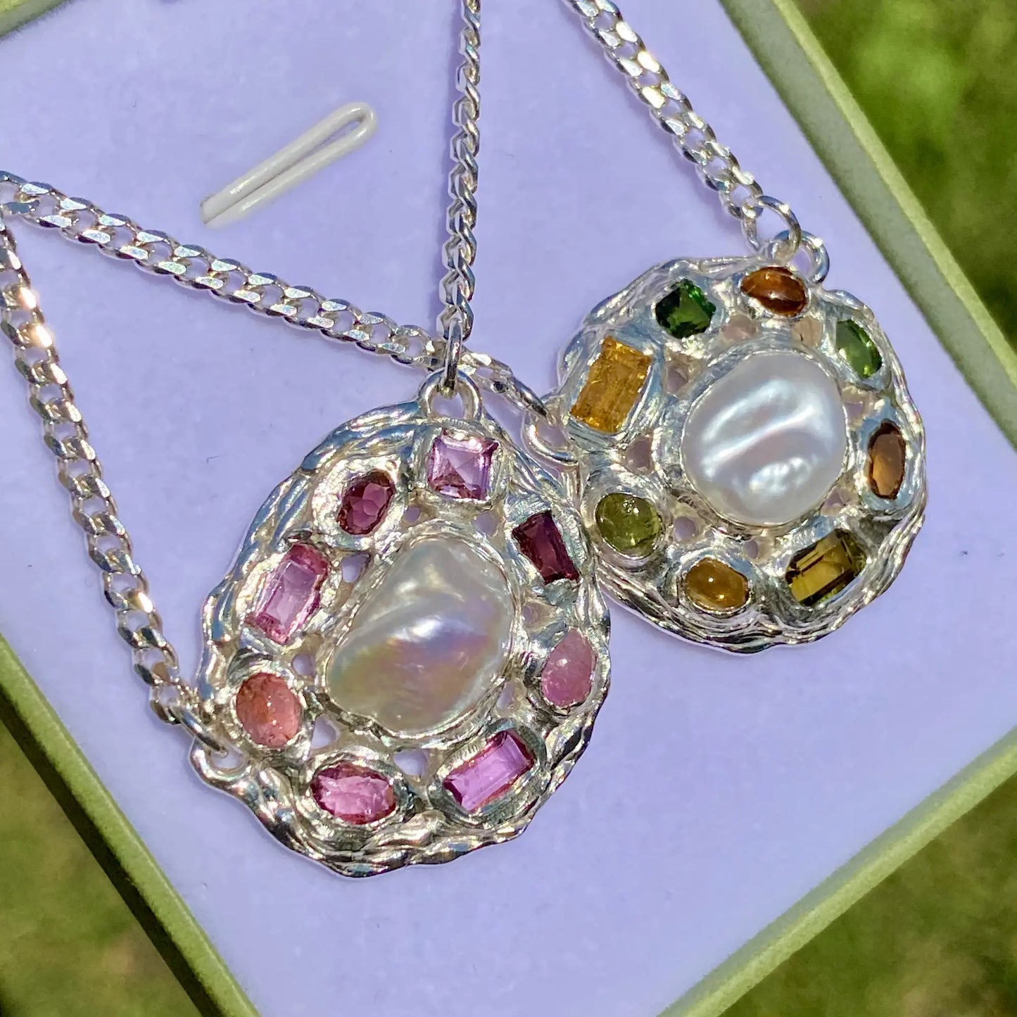 Pair of earrings with pearl and gemstone design on a light purple background