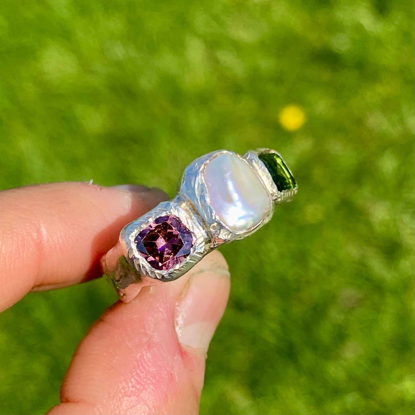 Jewel Tapestry Ring features a pearl, a green tourmaline, and a pink spinel stone. Handmade from sterling silver, this ring comes in a single size: O or 7.