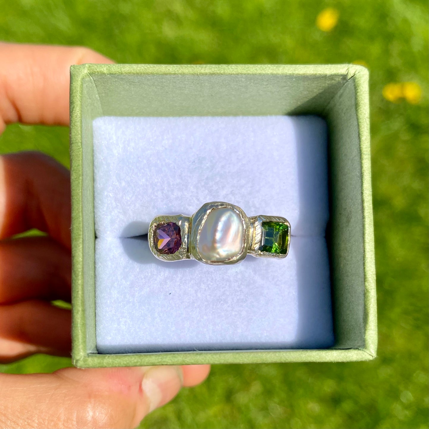 Jewel Tapestry Ring features a pearl, a green tourmaline, and a pink spinel stone. Handmade from sterling silver, this ring comes in a single size: O or 7.