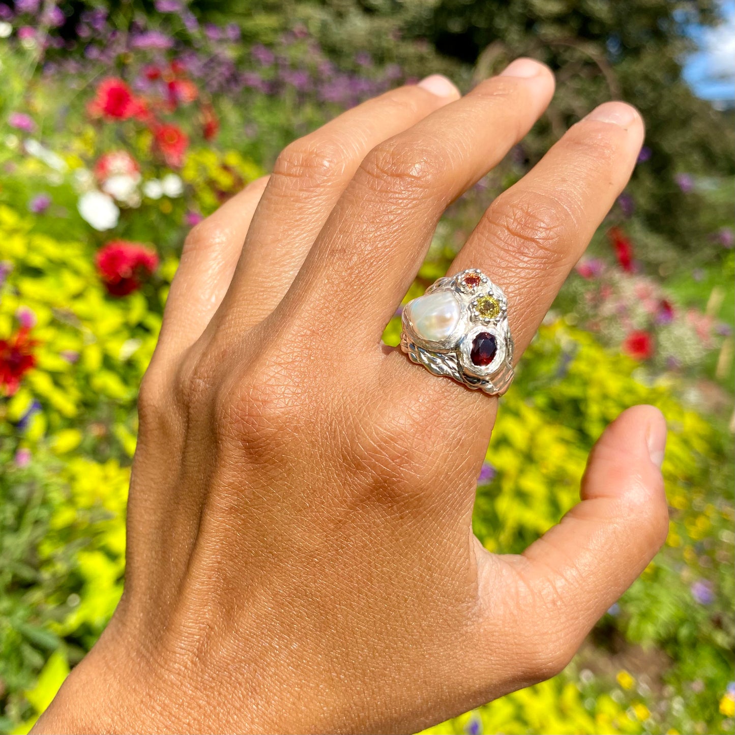 The Melodi features a thick band with four stones: a Keshi pearl, a red garnet, yellow and orange sapphires. The ring is available in size ;O 1/2 (US 7 1/4).