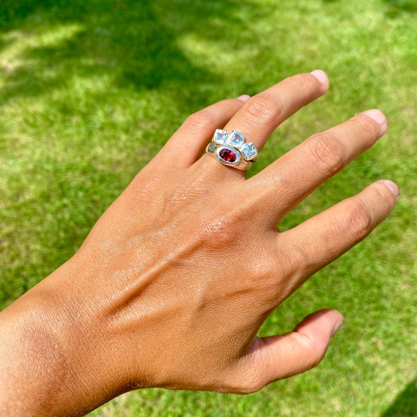 The Ocean Blossom ring stack comes as a set of two. One ring features three light blue aquamarine stones, and the other has a red oval garnet stone. Handmade by me from sterling silver, these stacking rings are available in one size: M (US 6)