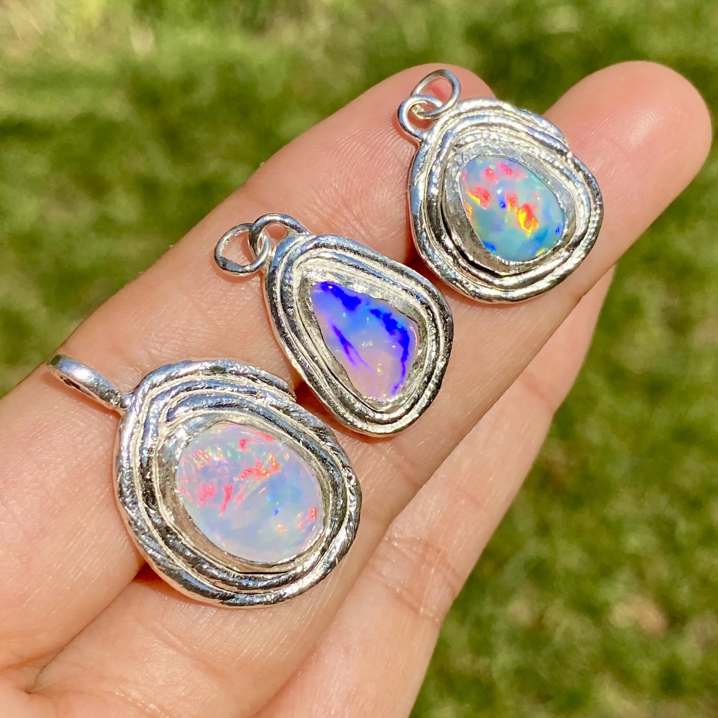 The three Opal Nest silver pendants on a single hand