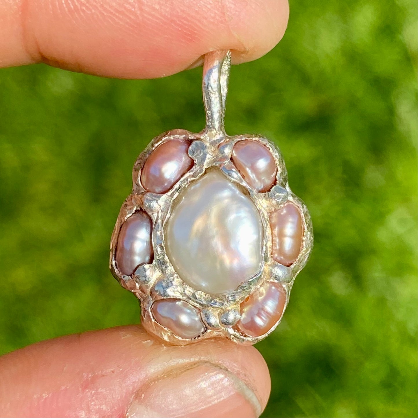Sakura Bloom Pendant is a handcrafted pendant featuring a white keshi pearl at its center, surrounded by a cluster of six delicate pink pearls. This design evokes the delicate beauty of springtime cherry blossoms in full bloom.