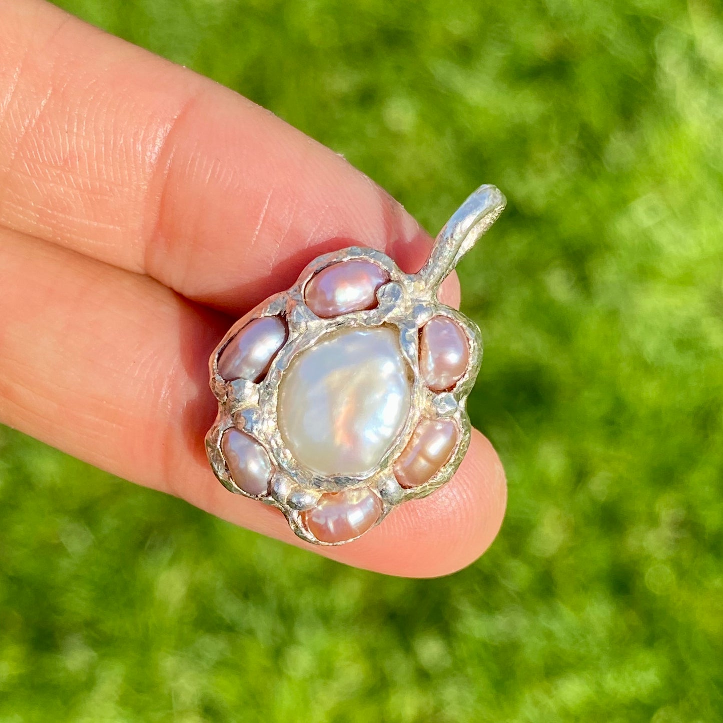 Sakura Bloom Pendant is a handcrafted pendant featuring a white keshi pearl at its center, surrounded by a cluster of six delicate pink pearls. This design evokes the delicate beauty of springtime cherry blossoms in full bloom.