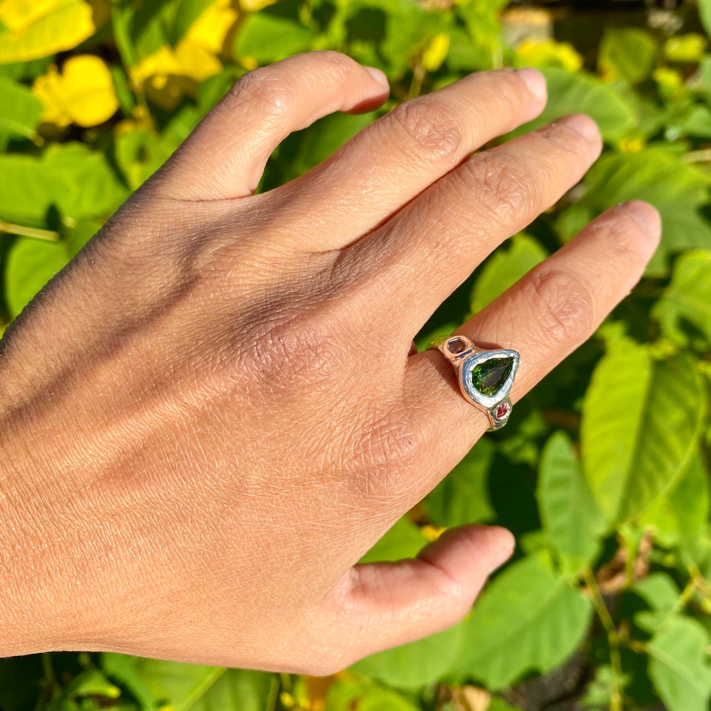 The Teardrop Glow ring features a thick band with three stones: A green tourmaline, pink and orange sapphire. Handmade by me, this ring is available in size M 1/2 (US 6 1/4).