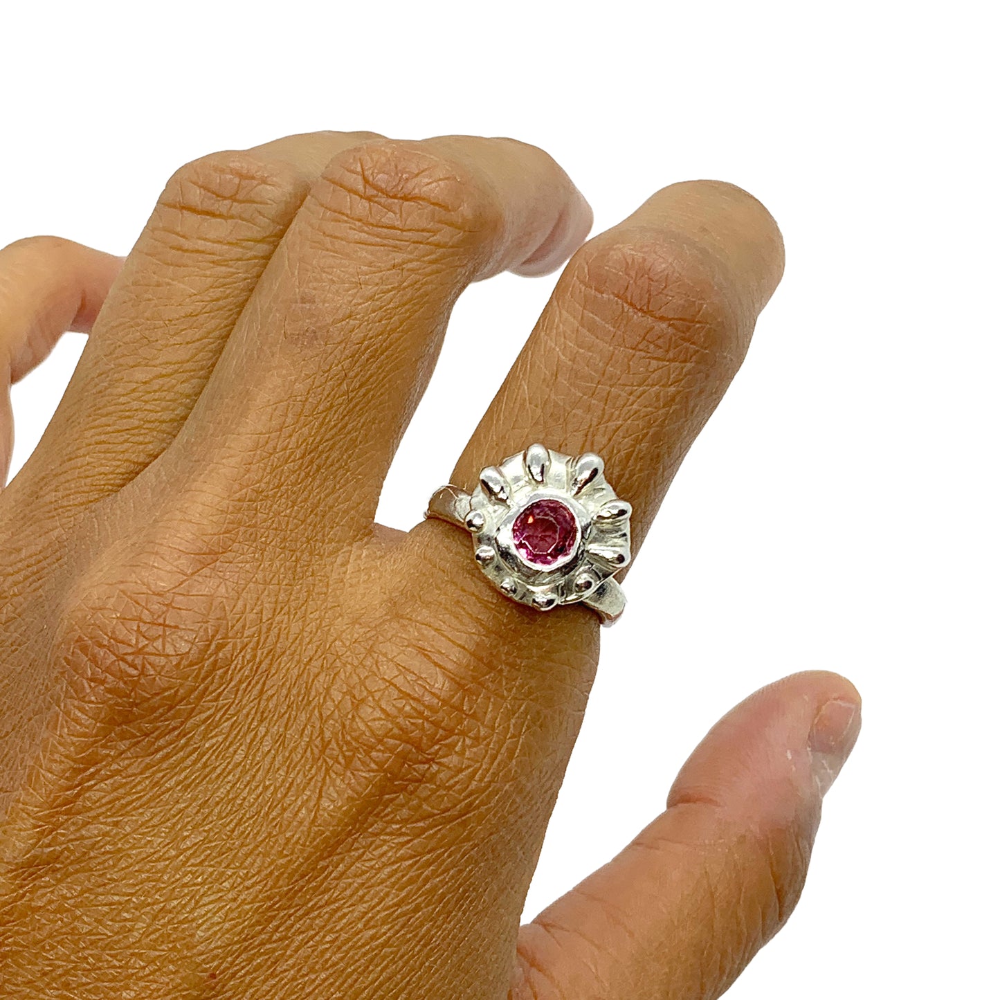 Introducing the Raffles Ring, a fun and casual silver ring that features a pretty pink tourmaline stone in the middle and a bumpy pattern around the stones that gives it a unique and playful look. It's perfect for everyday wear.
