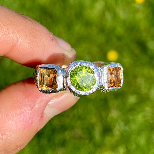 Citrus Garden Ring features a green peridot stone and two square, yellow citrines on the sides. Handmade from sterling silver, this ring comes in a single size: N ½ (or 6 ¾).