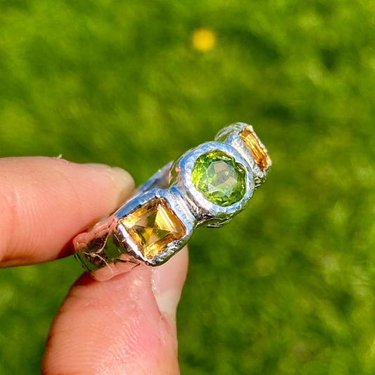 Citrus Garden Ring features a green peridot stone and two square, yellow citrines on the sides. Handmade from sterling silver, this ring comes in a single size: N ½ (or 6 ¾).