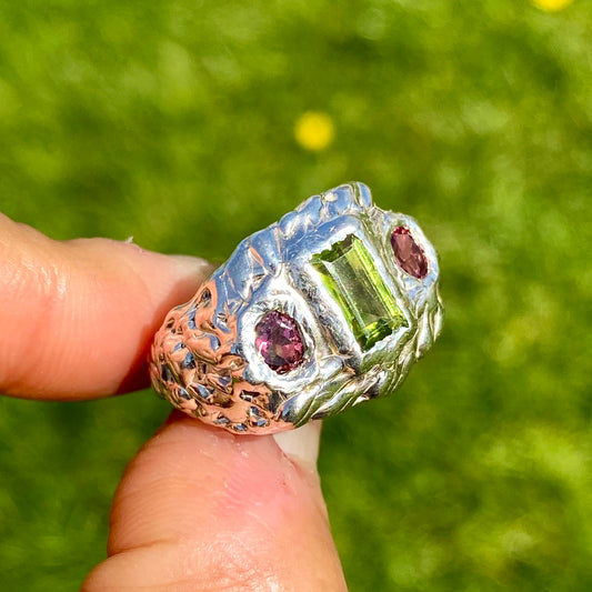 Cute Fish Face Ring features a green peridot stone and two pink tourmalines, set in a chunky band. Handmade from sterling silver, this ring comes in a single size: M ½ (or US size 6 ¼).