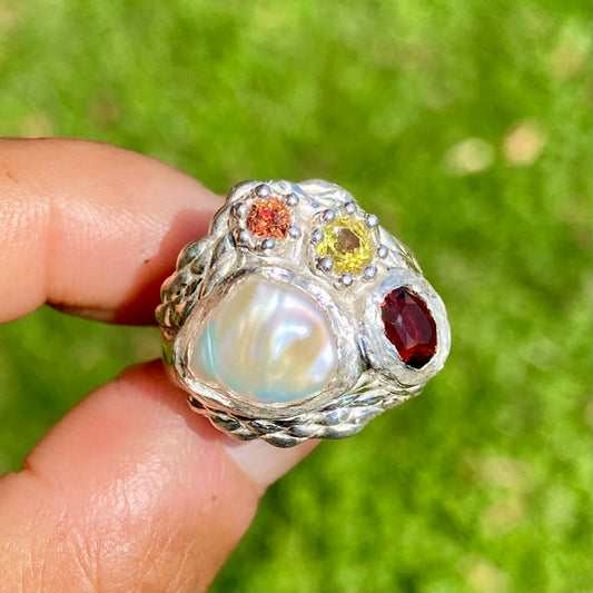 The Melodi features a thick band with four stones: a Keshi pearl, a red garnet, yellow and orange sapphires. The ring is available in size O 1/2 (US 7 1/4).
