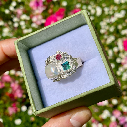 The Pearl Grove features a thick band with three stones: Keshi pearl, green square tourmaline, and pink round stone. Handmade by me from sterling silver, this ring is available in size O (US 7)