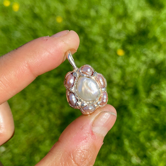 Sakura Bloom Pendant is a handcrafted pendant featuring a  white keshi pearl at its center, surrounded by a cluster of six delicate pink pearls. This design evokes the delicate beauty of springtime cherry blossoms in full bloom.