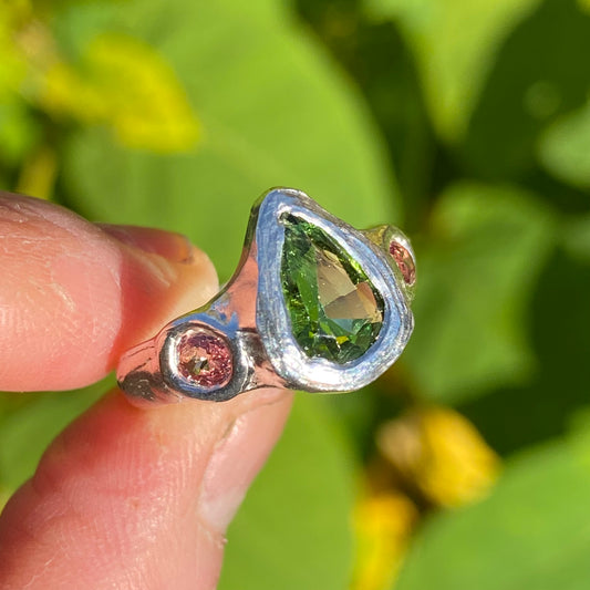 The Teardrop Glow ring features a thick band with three stones: A green tourmaline, pink and orange sapphire. Handmade by me, this ring is available in size&nbsp;M 1/2 (US 6 1/4).