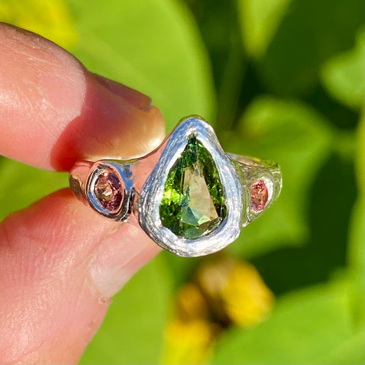 The Teardrop Glow ring features a thick band with three stones: A green tourmaline, pink and orange sapphire. Handmade by me, this ring is available in size&nbsp;M 1/2 (US 6 1/4).