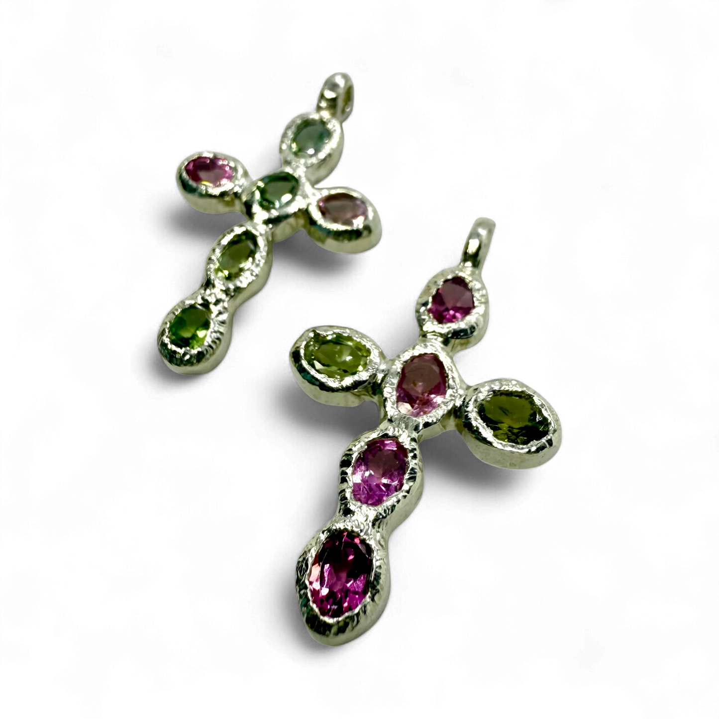 Close-up of Harmony Green and Pink Cross pendants, handmade in Paris from sterling silver with tourmalines.