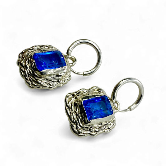 Front view of Astra Hoops showing sterling silver hoops with sparkling blue topaz stones.