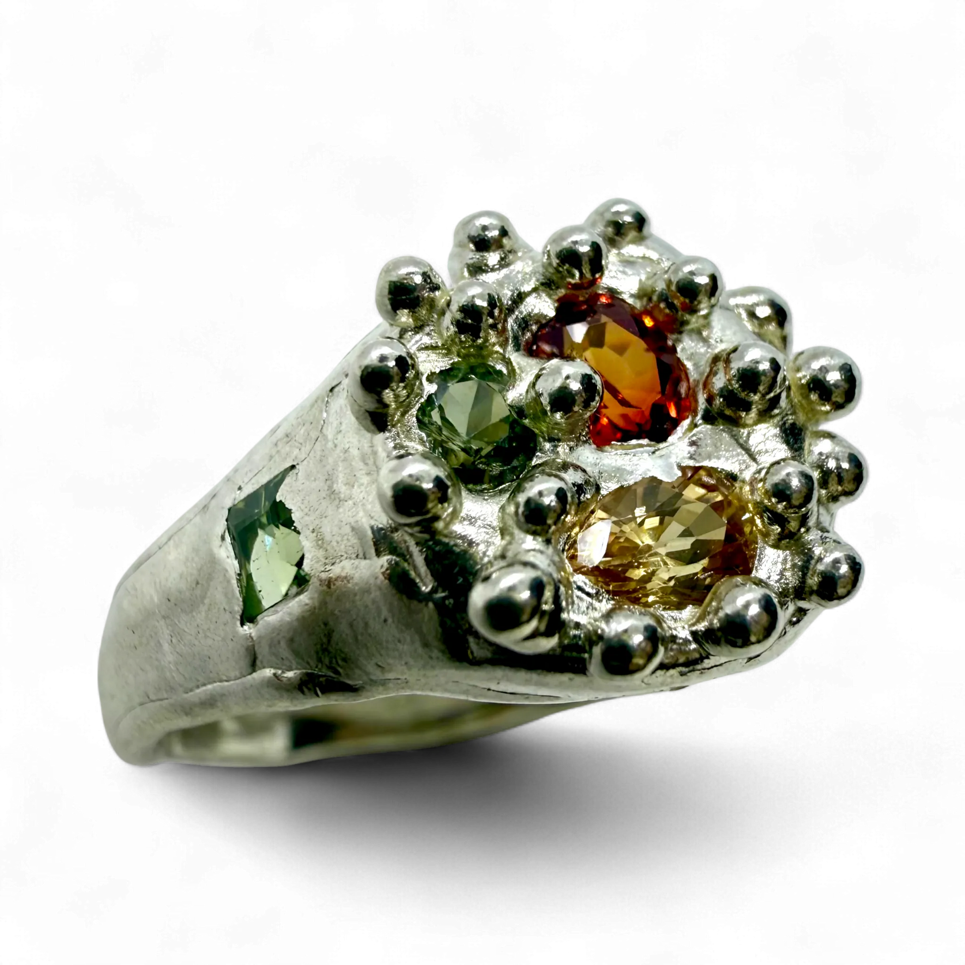 Close-up of Pijar Ring showing textured sterling silver band and colourful sapphires in orange, green, and yellow.