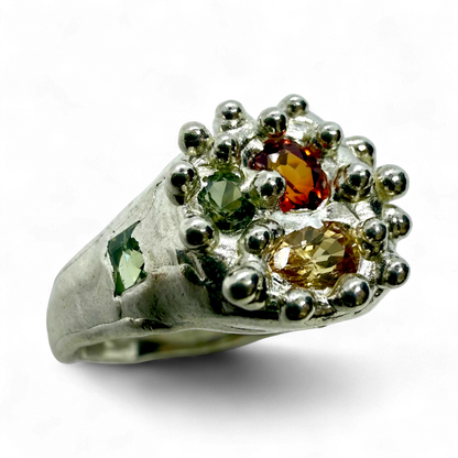 Close-up of Pijar Ring showing textured sterling silver band and colourful sapphires in orange, green, and yellow.