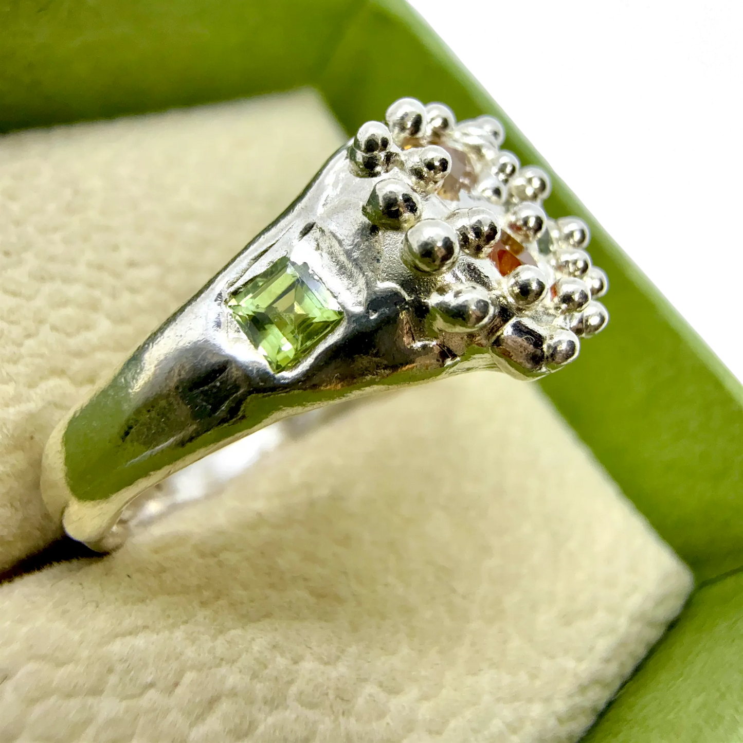 Side view of Pijar Ring highlighting organic silver form and vibrant sapphires in yellow, green, and orange tones.