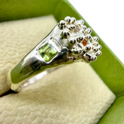 Side view of Pijar Ring highlighting organic silver form and vibrant sapphires in yellow, green, and orange tones.